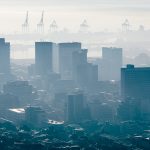 General view of cityscape with multiple modern buildings and cranes in the foggy morning. skyline and urban architecture.